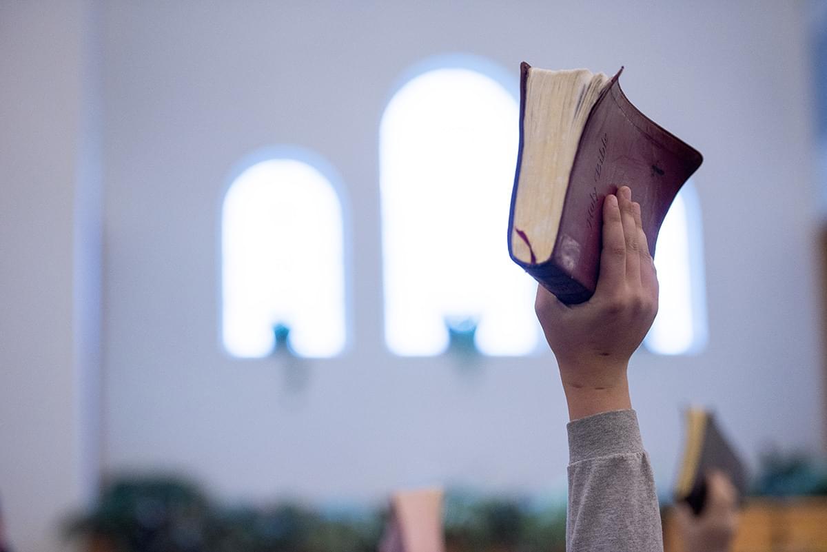 A closeup shot of a person holding up the bible with a blurred background
